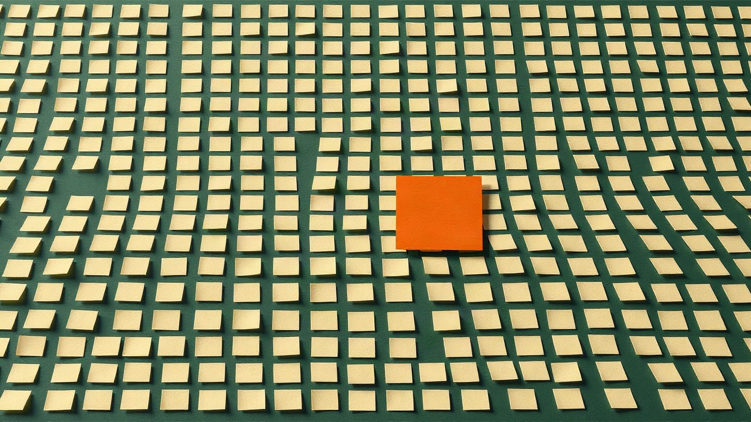 Un campo de cuadros de papel color crema y uno solo en terracota, apartado del resto